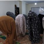 دانش‌آموزان در حال نماز جماعت در نمازخانه مدرسه با حضور فرهنگی و آموزشی