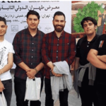 گروهی از دانش‌آموزان و تدریس‌کنندگان در نمایشگاه کتاب تهران، پشتِ بنر رسمی رویداد