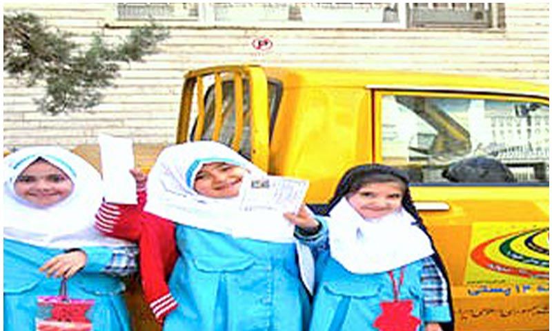 سه دختر دانش‌آموز در حال شرکت در فعالیت ساخت ماسک خلاقانه، کنار اتوبوس، به عنوان بخشی از رویداد یا پروژه هنری مدرسه