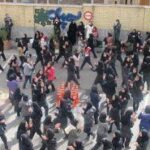 دانش‌آموزان با لباس فرم مدرسه در حیاط به‌صورت گروهی جمع شده‌اند در حین برگزاری یک مراسم یا جمع‌آوری دسته‌جمعی