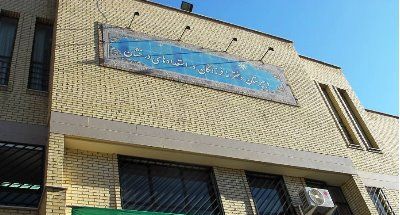 نمای خارجی ساختمان مدرسه فرزانگان با تابلوی دائم آبی رنگ و دیوار آجری زرد