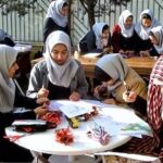 دانش‌آموزان دختری در حال شرکت در یک فعالیت هنری و خلاقانه در حیاط مدرسه، مشغول رنگ‌آمیزی و هنرهای دستی
