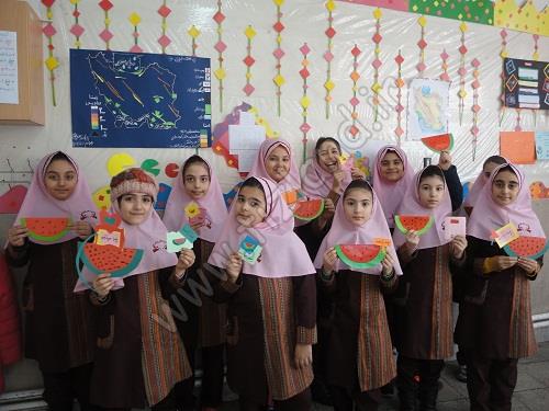 دانش‌آموزان دختر در حال نمایش محصولات پروژه هنری میوه‌های کاغذی رنگی در کلاس درس