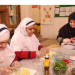 دانش‌آموزان در حال یادگیری مهارت‌های آشپزی و آماده‌سازی مواد غذایی در سالن آشپزی مدرسه