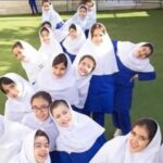 گروهی از دانش‌آموزان دختر با لباس فرم سفید و آبی در حیاط مدرسه