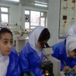 دانش‌آموزان دختر در حال انجام آزمایش علمی در آزمایشگاه مدرسه با تجهیزات و دستگاه‌های آزمایشی