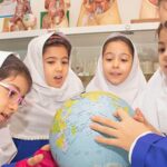 گروهی از دانش‌آموزان در حال کاوش و یادگیری جغرافیا با گلوب جغرافیایی در یک فعالیت یادگیری تعاونی