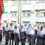 دانش‌آموزان مدرسه در حیاط حول پرچم ایران در حال شرکت در مراسم ملی