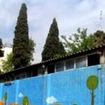 نمای خارجی دیوار ساختمان مدرسه با نقاشی‌های رنگی درخت‌های آبی و سبز