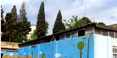 نمای خارجی دیوار ساختمان مدرسه با نقاشی‌های رنگی درخت‌های آبی و سبز