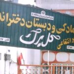 درب فلزی سبزرنگ با تابلوی دائمی نام و اطلاعات مدرسه