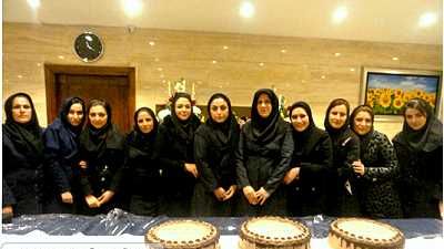 گروهی از دختران با حجاب درحال گرد‌هم‌آمدن پشت میزهایی پر از غذای مختلف در یک رویداد مدرسه‌ای