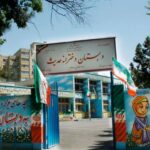 نمای بیرونی مدرسه ابتدایی با درب ورودی فیروزه‌ای و دیوار نقاشی شده با تصاویر کودکان