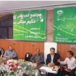 عکس جلسه اداری درون‌مدرسه با حضور کادر مدرسه که در اطراف میز نشسته‌اند و تابلوهای سبز آموزشی در پس‌زمینه دیده می‌شود