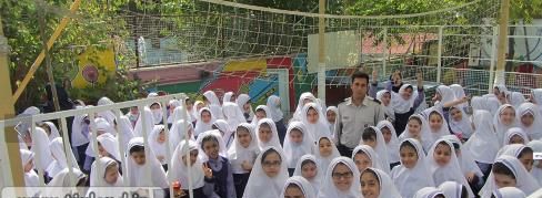 دانش‌آموزان دختر با روسری سفید در حال حضور در یک مراسم یا گردهمایی در حیاط مدرسه
