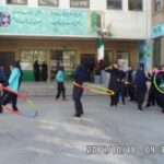 دانش‌آموزان مدرسه در حیاط در حال شرکت در فعالیت‌های ورزشی گروهی، کشتی‌ریسی و بازی‌های تیمی