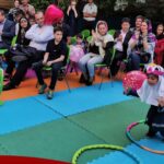 دانش‌آموزان و معلمان در حین شرکت در یک برنامه فعالیت‌های بازی‌ای و آموزشی گروهی در فضای باز با تجهیزات رنگی