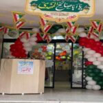 تصویری از ورودی مدرسه تزیین‌شده با پرچم ایران، بادکنک‌های رنگین و بنرهای آیینی برای برگزاری یک مراسم جشن