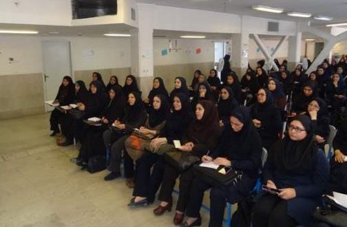 دسته‌جمعی از دانش‌آموزان پوشیده لباس یکسان نشسته در فضای داخلی در طول مراسم یا رویداد گروهی