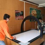 دانش‌آموزان در حال کار گروهی روی یک پروژه تکنیکی و فناوری‌ای با استفاده از تجهیزات تعاملی در کلاس درس