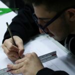 دانش‌آموز در حال انجام فعالیت رسم تکنیکی با خط‌کش و مداد بر روی کاغذ