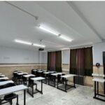 نمای داخلی کلاس درس مجهز با میز‌های فردی، صندلی‌های کلاسی، تابلو سیاه، درب‌های فلزی، پنجره‌ها و روشنایی فلورسنتی