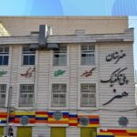 نمای جلویی سردر ساختمان مدرسه با تابلوی نام‌نویسی فارسی و معماری سنگ‌فریز