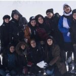 گروهی از دانش‌آموزان مدرسه در محیط برفانی، ایستاده کنار هم برای عکس یادگاری در یک سفر یا رویداد مدرسه‌ای
