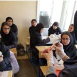 دانش‌آموزان در حال انجام یک فعالیت تشریح یا آزمایش علمی عملی، دستکش‌های پلاستیکی و تجهیزات آزمایشگاهی به دست دارند.