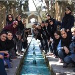 گروهی از دانش‌آموزان دختر در بازدید میدانی به باغ تاریخی با معماری سنتی و آب‌رو