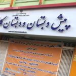 تابلوی ورودی مدرسه با نام و وبسایت و اطلاعات تماسی، کنار علامت پارکینگ ممنوع