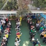 تجمع دانش‌آموزان و معلمان در حیاط مدرسه برای یک رویداد یا مراسم گروهی، با حضور افراد زیاد و سازمان‌بندی دایره‌ای