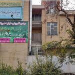 نمای بیرونی ساختمان مدرسه خاجه ناصرالدین طوسی با معماری آجری، پنجره‌ها، درب‌های فلزی و بنرهای معرفی‌کننده