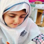 دختر دانش‌آموزی با روسری در حال انجام فعالیت و کار پروژه‌ای در کلاس درس