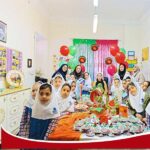 دانش‌آموزان دختر در حال شرکت در یک رویداد کلاسی با تزئینات رنگی و فعالیت‌های گروهی در درون کلاس
