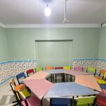 کلاسی با دیوارهای سبز، میزهای رنگین، صندلی‌های چندرنگ، و تخته‌سفید؛ فضایی نوین و پویا برای یادگیری