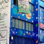 نمای بیرونی درب ورودی مدرسه کیامهر با تابلو‌های راهنما و دکوراسیون فضایی روی واجهه ساختمان