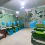 کلاس درسی تزیین‌شده با بادکنک‌های آبی و تزئینات رنگی درآویز برای برگزاری جشن یا رویداد دانش‌آموزان