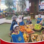 دانش‌آموزان دبستان در حال نمایش سبدهای میوه‌ها و سبزیجات مختلف در یک فعالیت آموزشی درون مدرسه