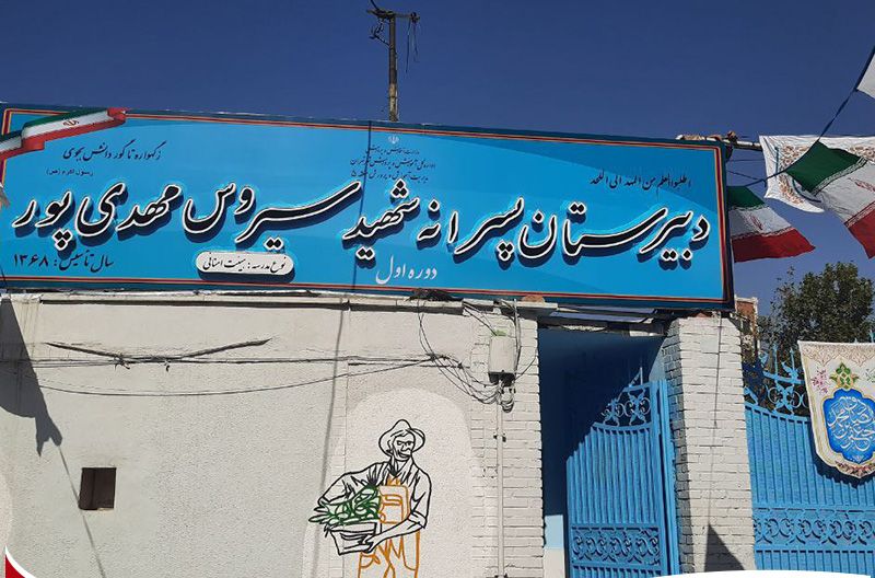 درب و سردر ورودی دیرستان با تابلوی آبی و درب‌های فیروزه‌ای رنگ