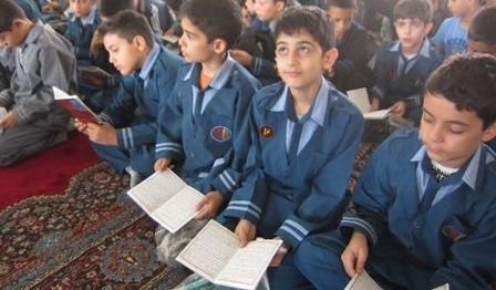 گروهی از دانش‌آموزان پوشنده یونیفرم آبی در یک مراسم دسته‌جمعی در حال تکمیل و امضاء کاغذ