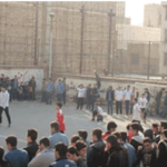 دانش‌آموزان مدرسه در حال فعالیت ورزشی و بازی گروهی در حیاط، برخی تماشاگر ایستاده‌اند