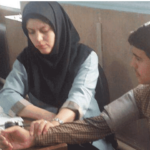 معلمی در حال راهنمایی و کمک به دو دانش‌آموز در یک درس عملی و فعالیت آموزشی گروهی داخل کلاس