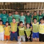 گروهی از دانش‌آموزان در لباس‌های سبز و زرد ایستاده در سالن ورزشی مدرسه برای عکس یادگاری تیم والیبال