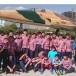 گروه بزرگی از دانش‌آموزان و معلمان در لباس یکپارچه قرمز و سفید در حیاط مدرسه برای مراسم یا برنامه‌ی هماندیشی