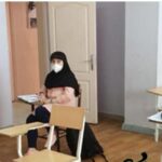 کلاس درس مدرسه‌ای با میز‌ها و صندلی‌های چوبی روی زمین چوبی و دیوارهای سفید