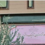 سردر و ورودی مدرسه با تابلوی نام و برگ‌های سبز درخت