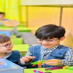 دانش‌آموزان دبستانی در کلاس درس با دیوارهای رنگین در حال انجام فعالیت‌های هنری و آموزشی