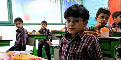 گروهی از دانش‌آموزان در حال فعالیت‌های تعلیمی مختلف در کلاس درس با میزهای سبز