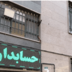 نمای جلویی ساختمان مدرسه با تابلوی نئون سبز و سردر معماری آجری